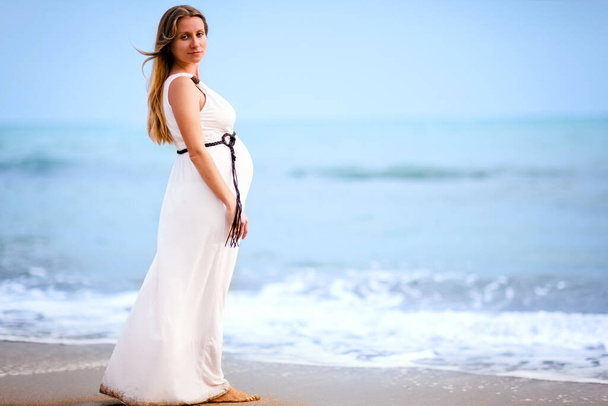 Pregnant lady standing on beach near sea - Фото, зображення