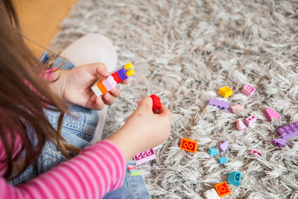 Little girl play with toy blocks on floor at home  - Foto, afbeelding