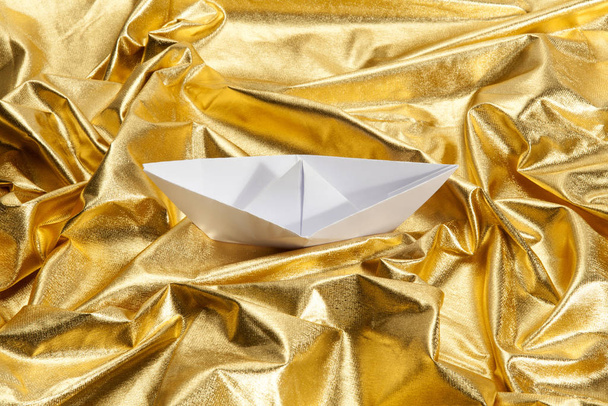 papieru origami łodzi żeglarstwo w złoto tkaniny niepewny wody. Kompozycja luksusowa. Minimalny kolor martwa Fotografia. - Zdjęcie, obraz