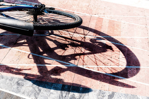 πίσω τροχός ποδηλάτου και η σκιά του σε πλακόστρωτα - Φωτογραφία, εικόνα
