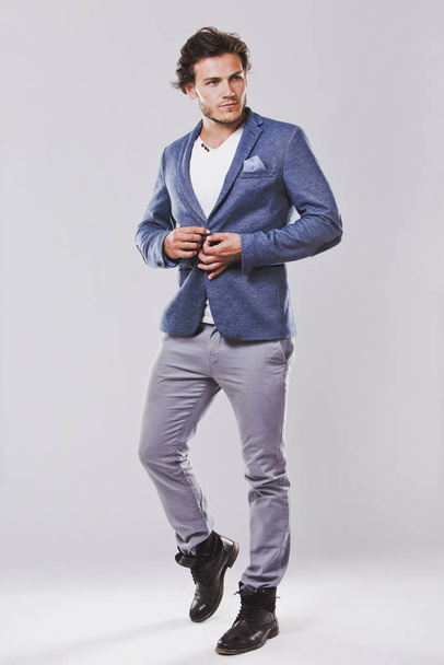 Fashion portrait of a handsome man with trendy hairstyle in a stylish jacket on light background - Zdjęcie, obraz