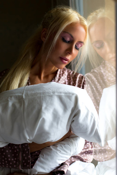 Blonde woman standing at the window - 写真・画像