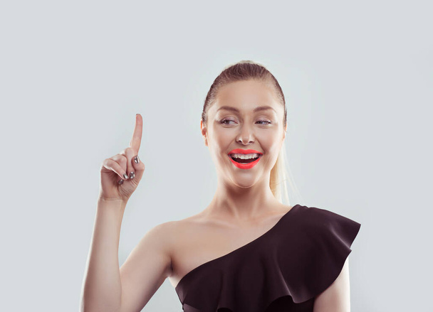 Portrait happy beautiful excited woman pointing with finger up isolated on white light gray wall background. Positive human face expressions, emotions, feelings body language, perception - Foto, afbeelding