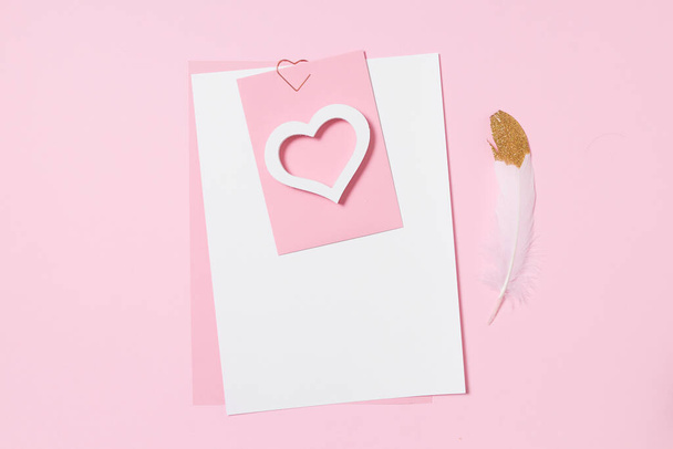 Leere Vorlage für romantische Buchstaben auf rosa Hintergrund. weiße Feder mit Vergoldung. echtes Foto, flache Lage. Kopierraum für Text. - Foto, Bild