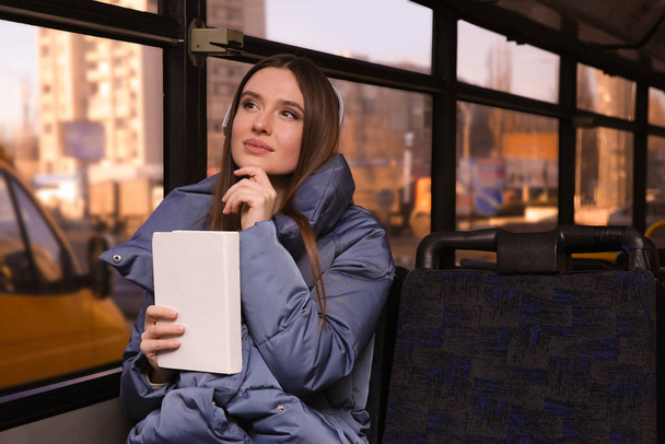 Woman listening to audiobook in trolley bus - Foto, Imagen