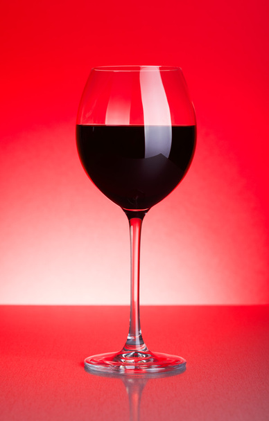 Glass of red wine on red - Фото, изображение