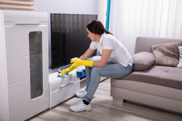 Side View Of A Young Female Janitor Cleaning Furniture At Home - Foto, immagini
