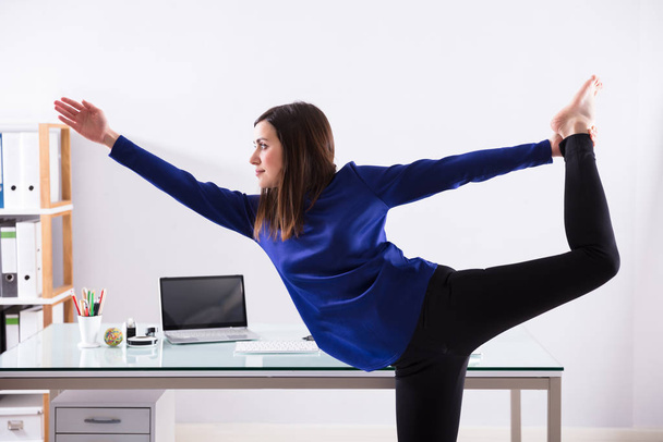 Young Businesswoman Looking At Invoice On Computer Doing Yoga - Foto, Imagen