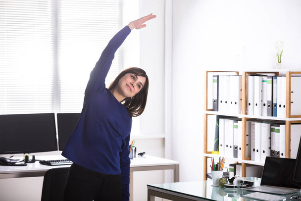Young Businesswoman Doing Stretching Exercise In Office - Photo, Image