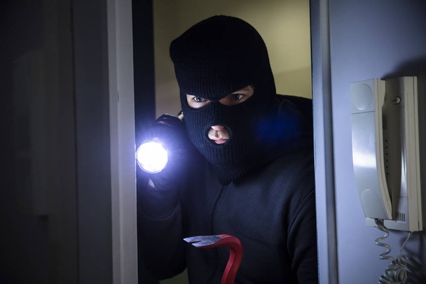 Thief With Flashlight And Crowbar Entering Into House - Foto, Bild