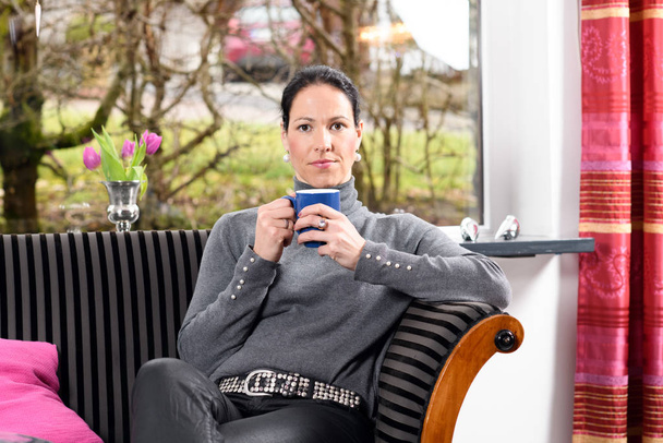 young dark haired woman at home with cup of coffeee relaxing - Фото, изображение