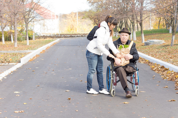 Daughter handing an elderly disabled man groceries - Φωτογραφία, εικόνα