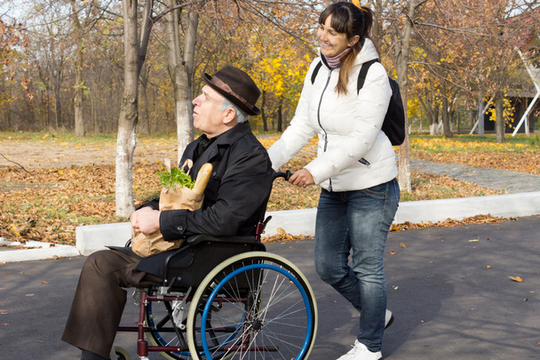 Happy woman helping a disabled elderly man - Foto, afbeelding