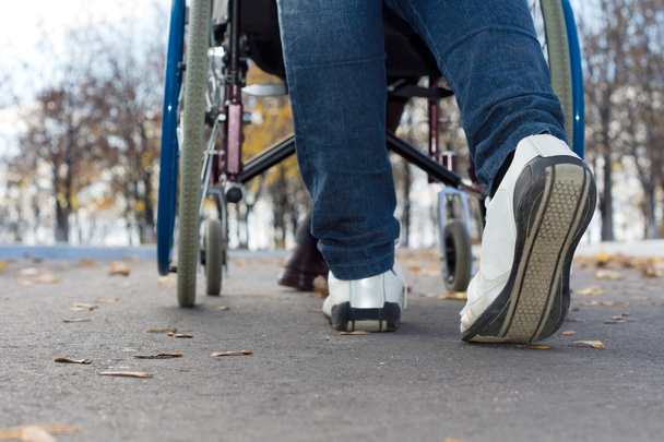 Feet of a person pushing a wheelchair - Φωτογραφία, εικόνα