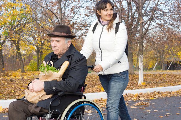 Smiling carer pushing an old man in a wheelchair - Φωτογραφία, εικόνα