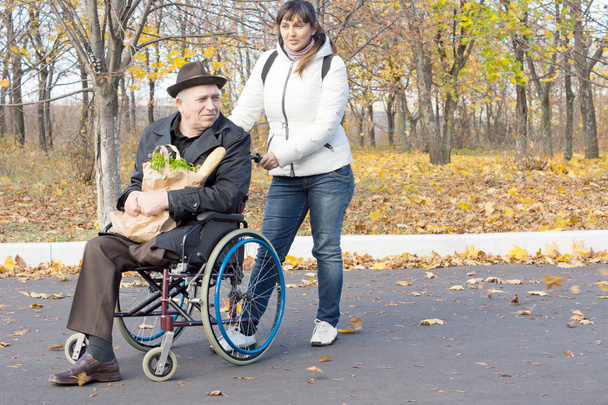 Woman helping a disabled pensioner in a wheelchair - Φωτογραφία, εικόνα