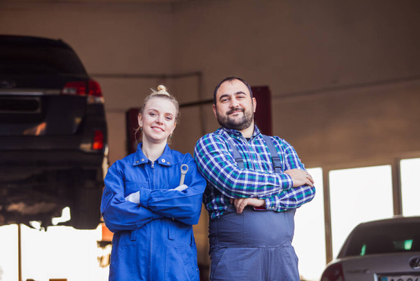 Confident young mechanics man and woman at garage - Φωτογραφία, εικόνα