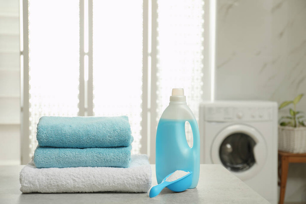 Clean towels and detergents on table in laundry room - Фото, изображение