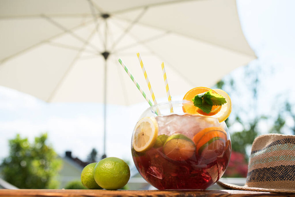 fresh sangria punchbowl in summer on terrace with white parasol - Photo, Image