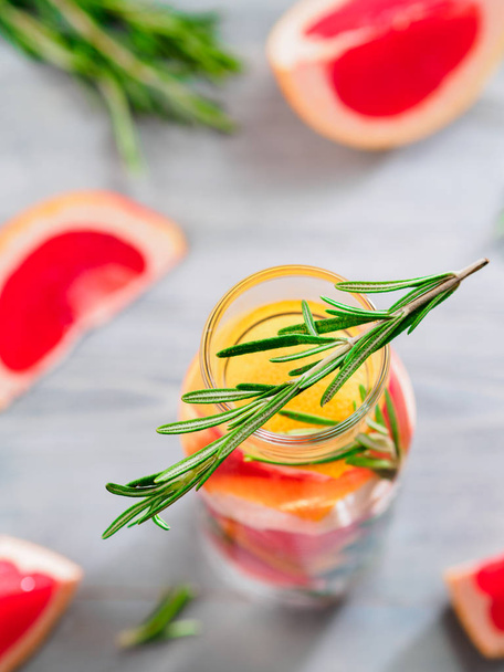 infused detox water with grapefruit and rosemary in glass bottle on gray wooden table. diet healthy eating and weight loss concept, copy space for text. Shallow DOF - Foto, Imagem