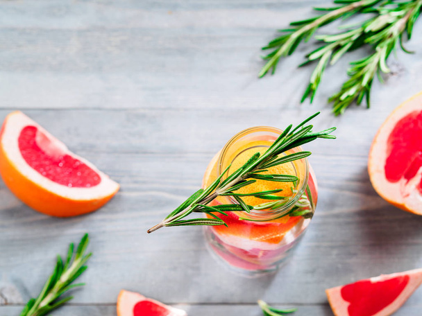 infused detox water with grapefruit and rosemary in glass bottle on gray wooden table. diet healthy eating and weight loss concept, copy space for text. Top view - Фото, изображение