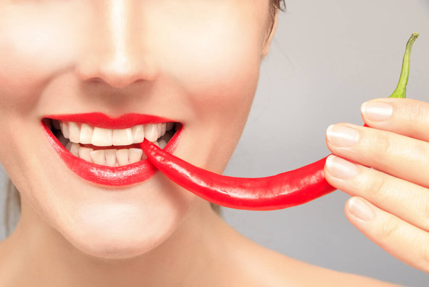 Beautiful woman teeth eating red pepper - Foto, afbeelding