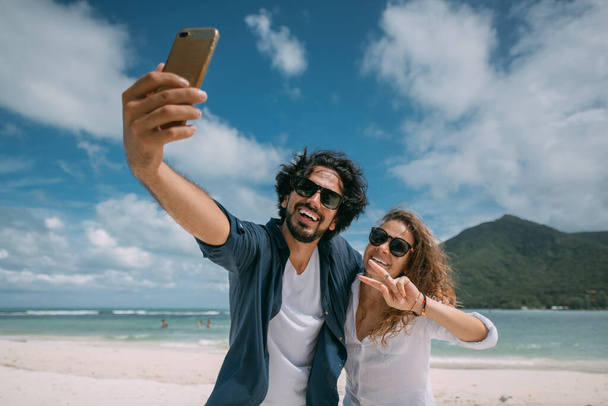 Un par de amantes se toman una selfie en una playa tropical
. - Foto, Imagen