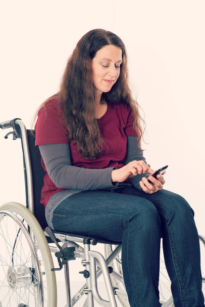 young woman in wheelchair using her smartphone - Foto, Imagen