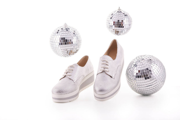 Fashion shoes, new modern silvery sneakers and mirror disco balls on white background. - Foto, immagini