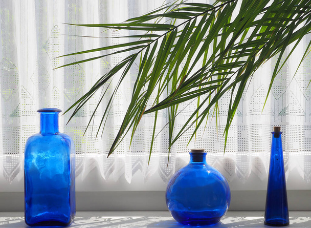 blue glass bottles on the windowsill - Zdjęcie, obraz