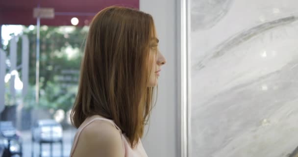 lady looks in mirror and turns posing in modern beauty salon - Felvétel, videó