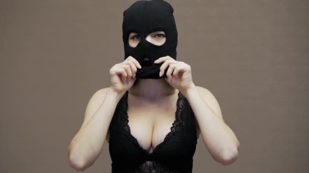 Sexy funny woman puts on hacker black balaclava mask, dressed in lace bra, robbery - Footage, Video