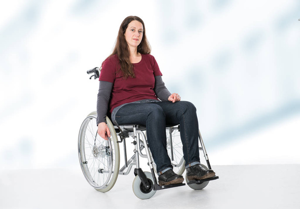 young woman in wheelchair in front of bright  background - Фото, изображение
