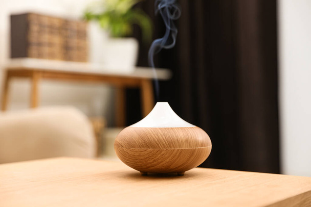 Aroma oil diffuser on wooden table at home. Air freshener - Foto, afbeelding