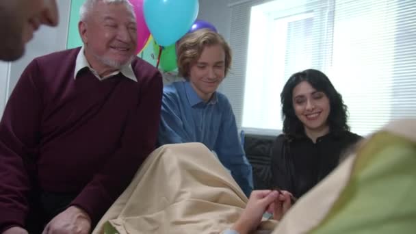 Matka, dědeček a další příbuzní sedí a mluví s dívkou, která leží na posteli v nemocnici - Záběry, video