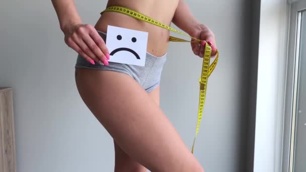 Stan zdrowia kobiety. Kobiecego ciała trzymając smutny uśmiech karty w pobliżu żołądka - Materiał filmowy, wideo