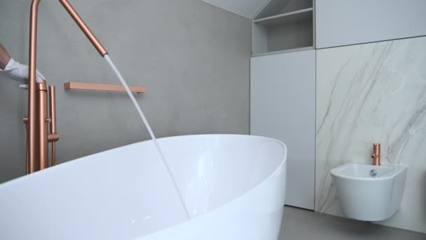 modernes stilvolles und luxuriöses Badezimmerinterieur mit weißer Badewanne und goldenem freistehenden Badewannenfüller. - Filmmaterial, Video