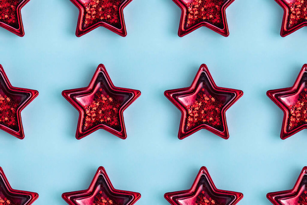 nahtloses Muster aus fünf spitzen roten metallischen Sternen auf pastellblauer Oberfläche. - Foto, Bild