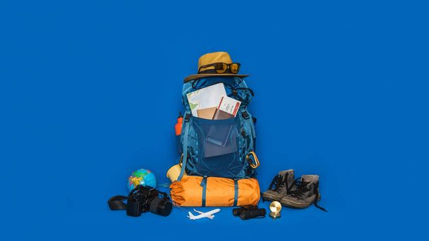 Tourist planning vacation with the help of world map with other travel accessories around. concept Luggage with accessory for travelers Vacation on Blue color background. Travel backpack - Zdjęcie, obraz