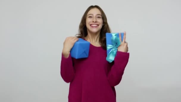 Fascinating excited brunette woman in pullover catching presents, holding gift boxes with expression of much joy - Filmagem, Vídeo