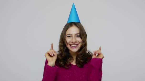 Excited happy brunette girl dancing with party cone on head, catching gift box saying wow, surprised by present - Imágenes, Vídeo