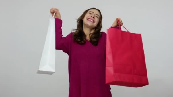 Happy enthusiastic shopper, joyful brunette woman in pullover holding shopping bags - Metraje, vídeo