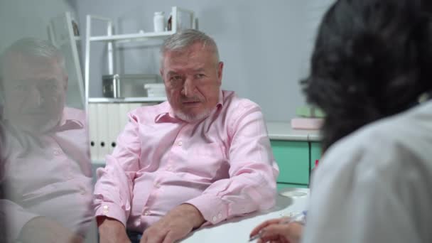 Muž sedí v nemocničním kabinetu a poslouchá pokyny lékaře  - Záběry, video