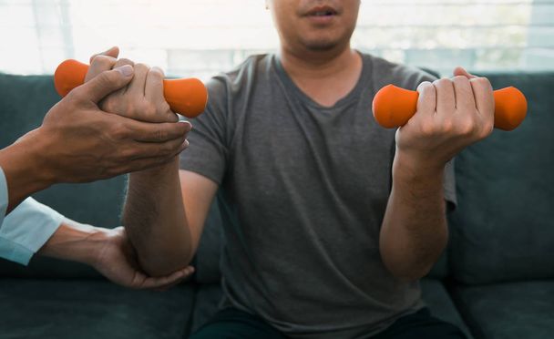 Asiático joven fisioterapeuta masculino ayudar a paciente con lifting du
 - Foto, imagen