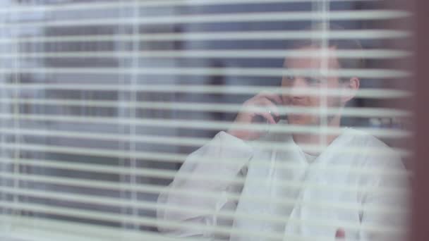 Άντρας με προστατευτικά ρούχα μιλάει στο τηλέφωνο στο εργαστήριο - Πλάνα, βίντεο