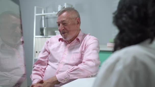 Old man sit in cabinet of hospital and speak with doctor - Video, Çekim