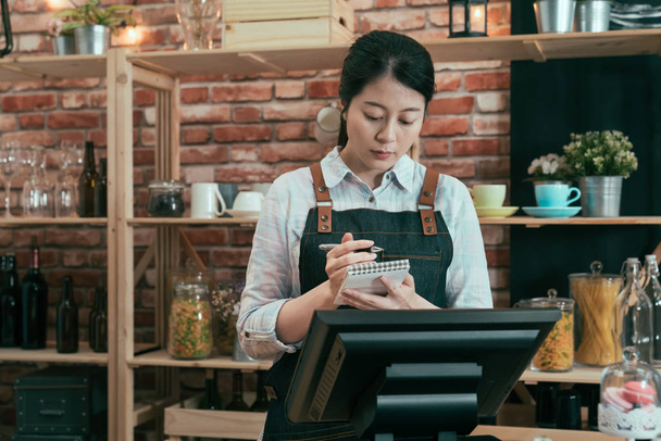 female worker in coffeehouse writing on note - Zdjęcie, obraz