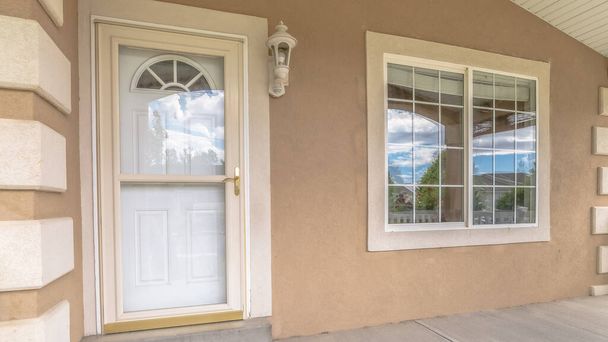Білі вхідні двері перед панорамою зі скляними панелями та вікнами біля входу в будинок. - Фото, зображення