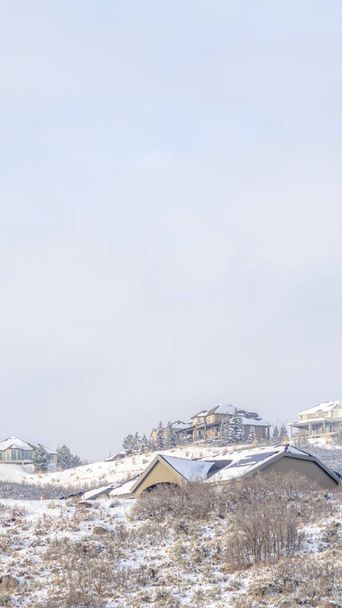Blog Fényképezés Vertical frame Snow covered hill top with snow houses against vast cloudy sky in winter - Fotó, kép