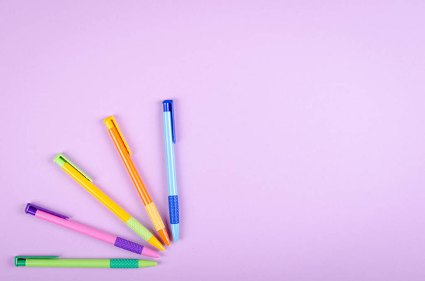 Different colored pens, school ballpoint on purple background composition. - Fotografie, Obrázek
